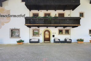 A traditional building with a balcony, a door with a glass panel, and two potted plants.