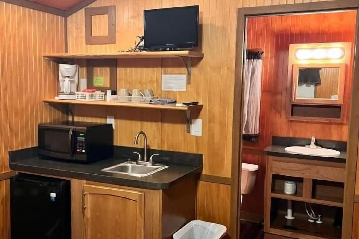 Cocina pequeña con microondas, lavamanos y refrigerador compacto.