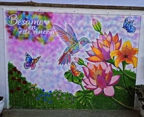 Un mural colorido con mariposas, flores y un colibrí.