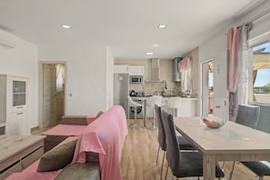 Un salon moderne avec un canapé, une table à manger et un coin cuisine à l’arrière-plan.