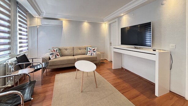 A modern living room with a sofa, a coffee table, a TV, and a small side table. - Curated Living in Nişantaşı (Istanbul)