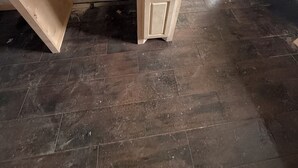 Um quarto com um armário de madeira, uma bancada branca e um piso estampado.