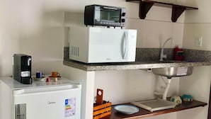 A compact kitchen with a white refrigerator, a microwave, and a coffee maker on the counter.
