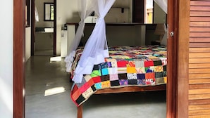 A bedroom with a canopy bed, a visible bathroom, and a wooden door frame.