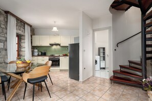 A modern kitchen with white cabinets, a black refrigerator, and a dining area with a glass table and chairs. - Apartment Nino for 4 persons near Porec with a beautiful panoramic view (Dračevac)