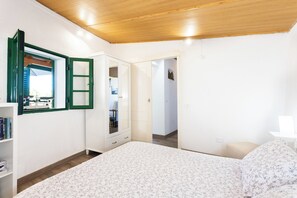 Ein Schlafzimmer mit einem Bett, einem Kleiderschrank, einem Spiegel und einer Tür zu einem anderen Raum.