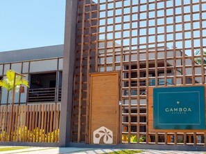 A modern building with a wooden lattice facade, a prominent entrance with a door, and a signboard with the name 'GAMBOA PATAONO'. - Gamboa Oasis Patacho 180m Praia Patacho (Porto de Pedras)