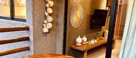 Una mesa de madera con un logotipo, una pared decorada con conchas, una lámpara de pared y un televisor.