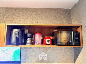 A kitchen shelf with a coffee maker, a blender, and a microwave.