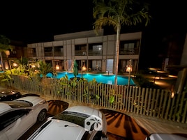 Um hotel com piscina, várias varandas e área de estacionamento com carros.