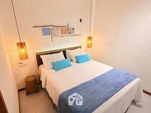 A neatly made bed with a blue and white bedspread, two pillows, and a wooden headboard.