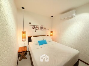 A hotel room with a bed, bedside tables, wall-mounted lamps, and a decorative wall piece. - Gamboa Oasis Patacho 180m Praia Patacho (Porto de Pedras)