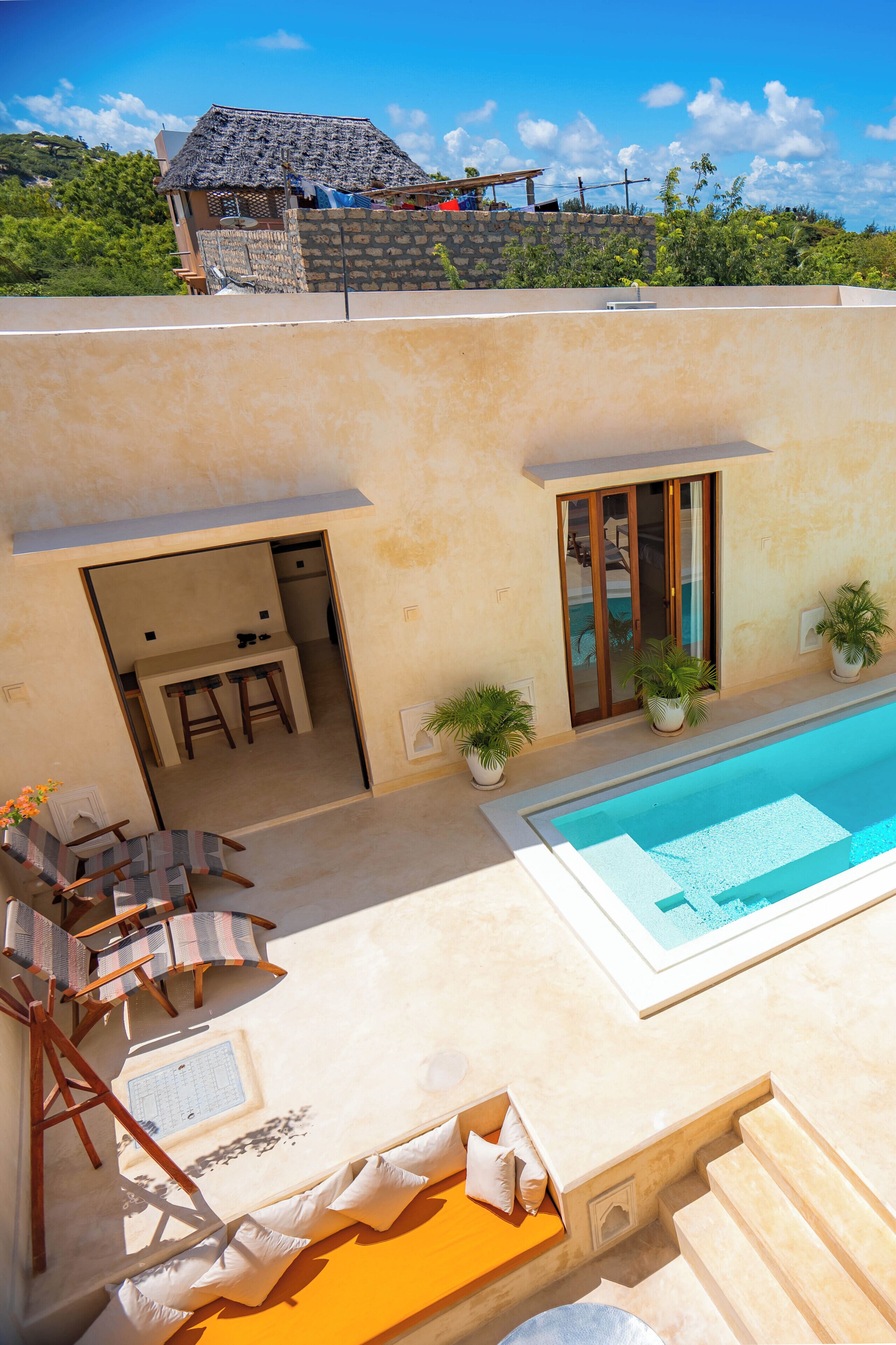 A poolside area with a seating arrangement, a small kitchen, and a view of the surrounding landscape.