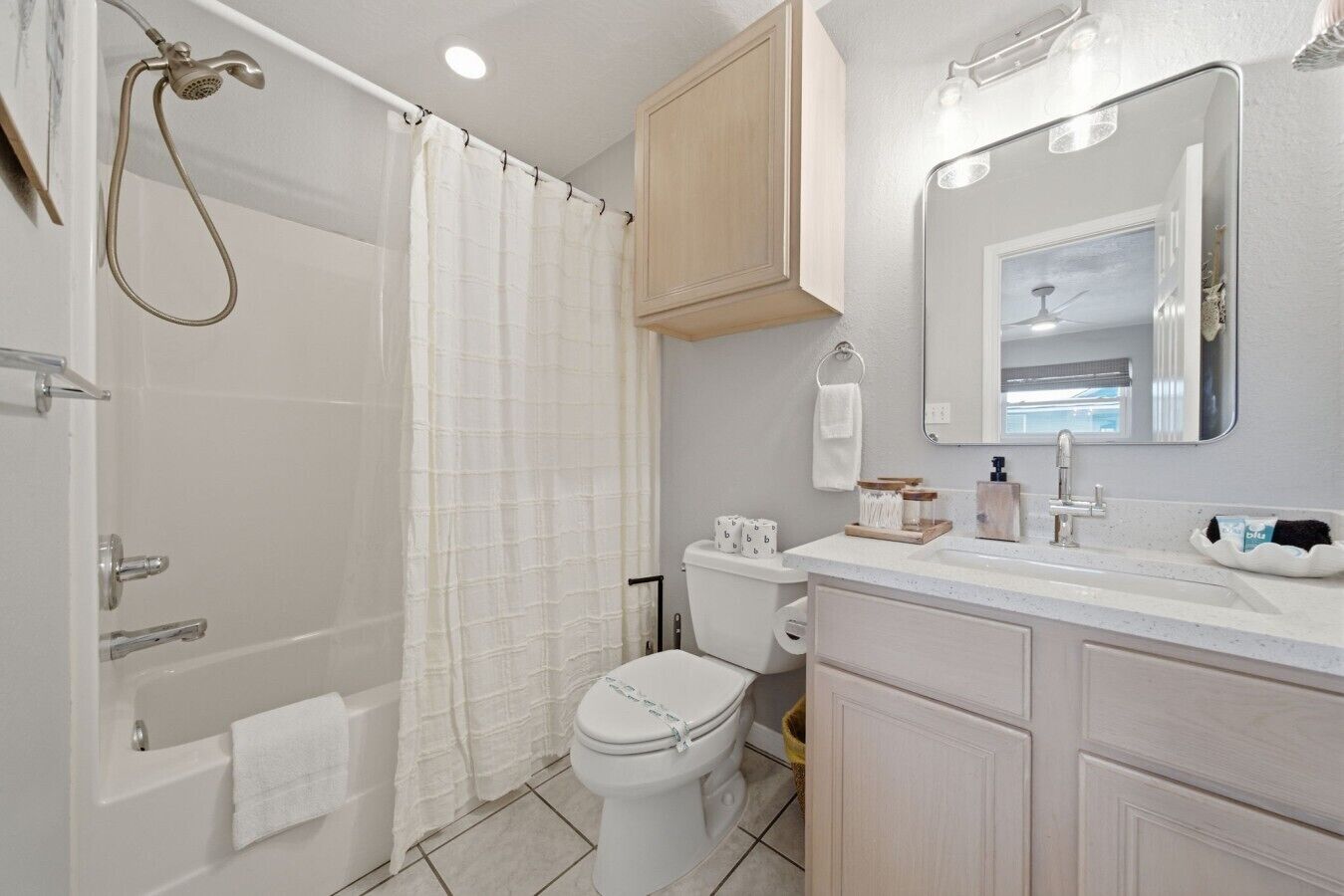 A bathroom with a shower, toilet, sink, and mirror.