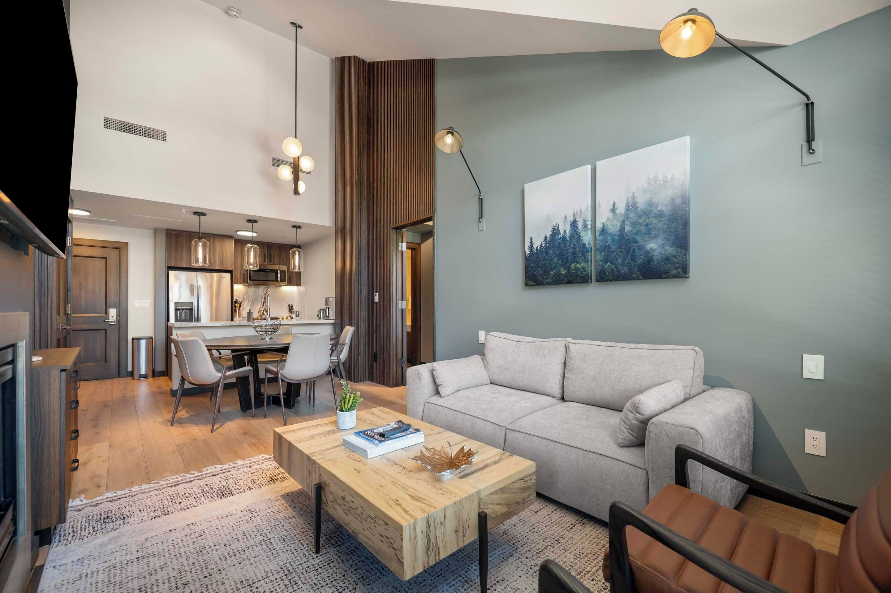A modern living room with a gray sofa, wooden coffee table, and pendant lighting.