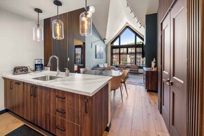 A modern kitchen with a large island, wooden cabinets, and pendant lighting. - Capitol Peak Lodge 3518 (Snowmass Village)