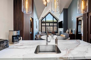 Una cocina moderna con una isla grande, electrodomésticos de acero inoxidable y vistas a través de un ventanal.