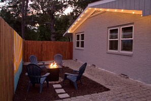 Eine Terrasse mit Feuerstelle, vier Stühlen und einem Holzzaun.