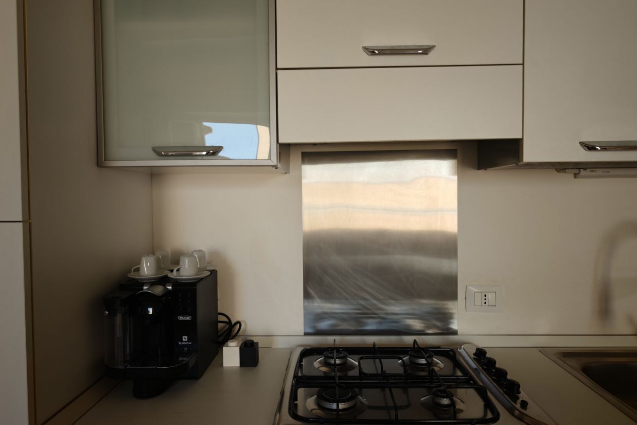 Une cuisine équipée d’une cuisinière à gaz, d’une machine à café et d’une hotte aspirante en acier inoxydable.