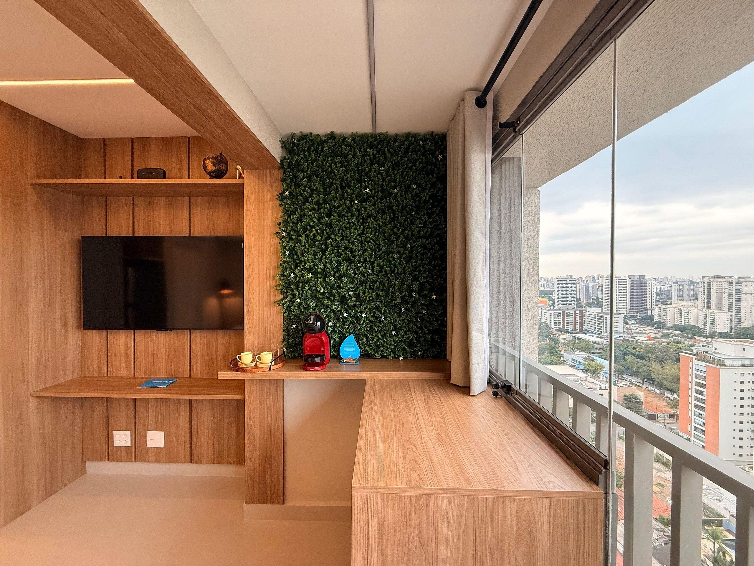 Un apartamento moderno con televisor, cafetera y una pared verde.