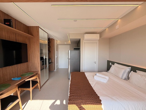 Habitación de hotel moderna con cama, escritorio, televisor y armario.