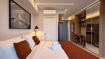 Una habitación de hotel con cama, escritorio, armario y una obra de arte con vistas a la ciudad.