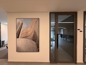 En modern inredning med ett stort, inramat arkitekturfoto på väggen, en glasdörr som leder till en korridor och en skylt som visar rum nummer 3 och 4.