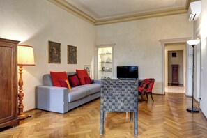 A living room with a sofa, a television, a small table, and a lamp. - Fossi Apartment by Mamo Florence (Firenze)