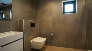 A modern bathroom with a toilet, a shower area, and a mirror. - Holiday Home in Kampen With Terrace (Kampen)