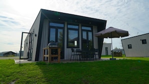 A modern two-story building with large windows, a patio with outdoor seating, and a grill. - Holiday Home in Kampen With Terrace (Kampen)