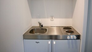 Una cuina compacta amb un rentaplat de superfície inoxidable, dues fogueres i un frigorífic integrat.