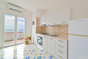 A modern kitchen with a large window, a balcony, and a view of the sea. - Tides (Barano D'ischia)