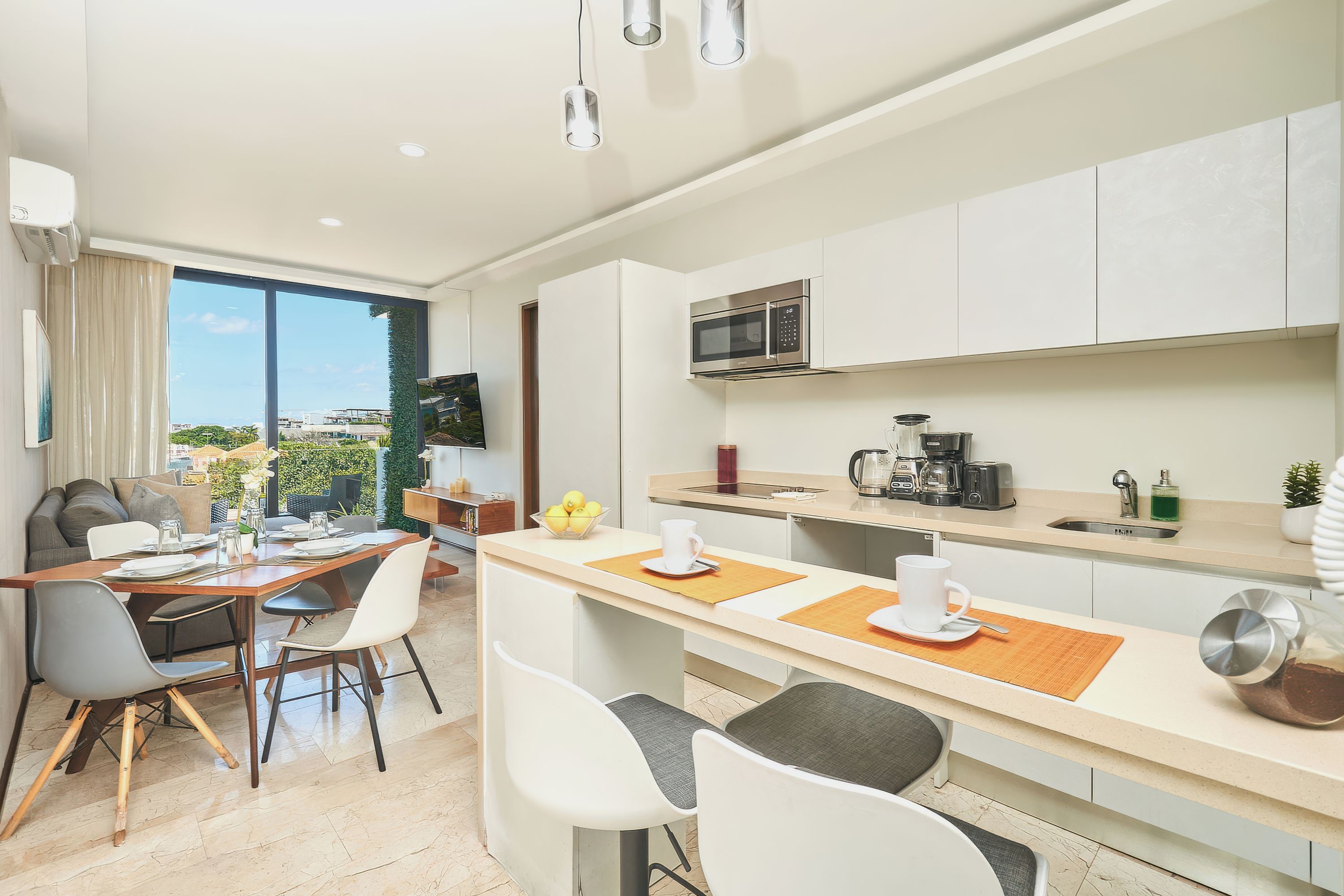 Una cocina moderna con microondas, cafetera y comedor con mesa y sillas.