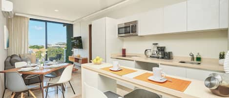 Una cocina moderna con microondas, cafetera y comedor con mesa y sillas.