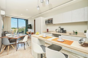 Een moderne keuken met een magnetron, koffiezetapparaat en een eethoek met tafel en stoelen.