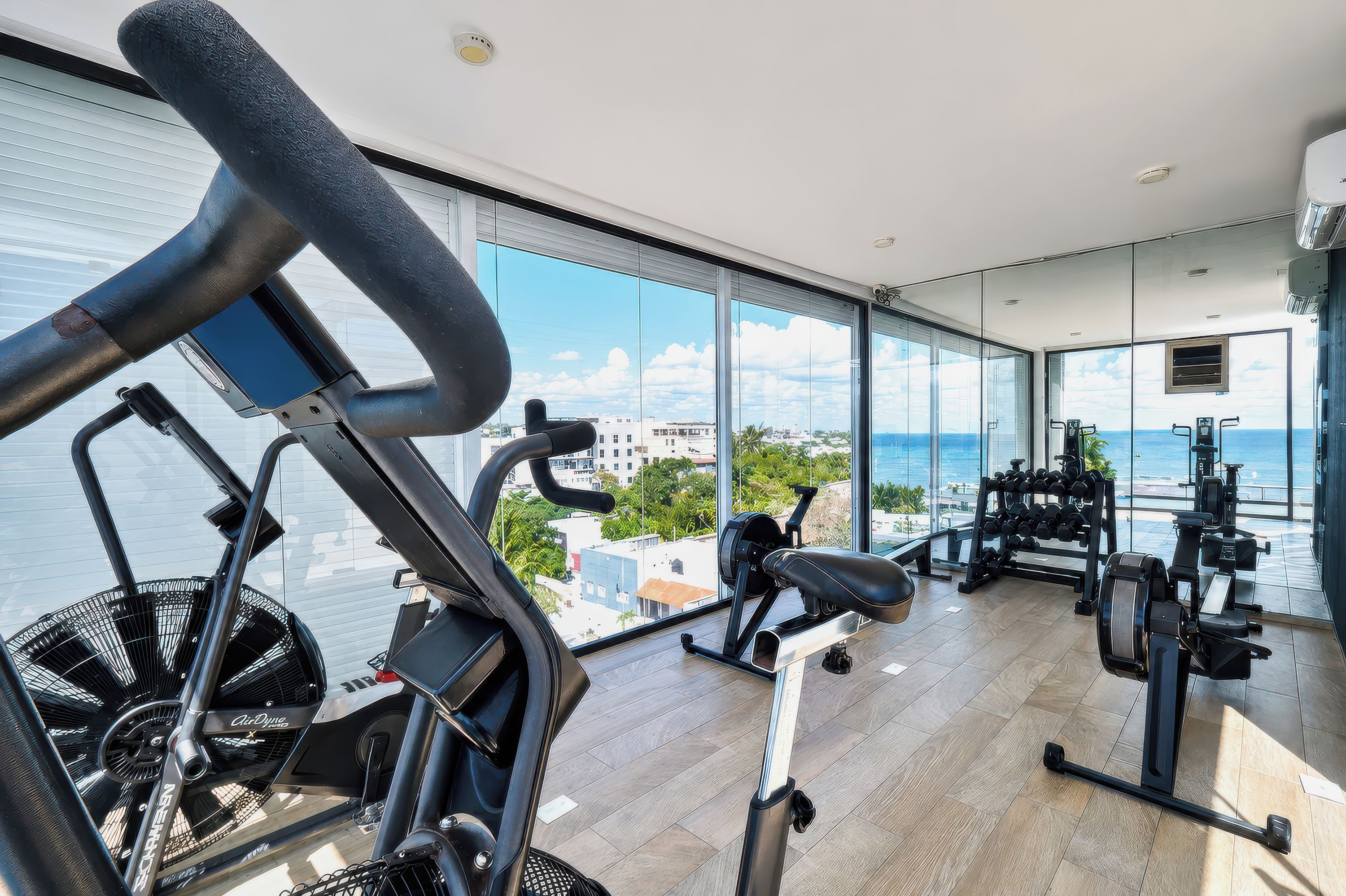 Un gimnasio con equipo de ejercicio y vistas al mar.