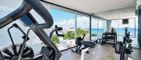 Un gimnasio con equipo de ejercicio y vistas al mar.