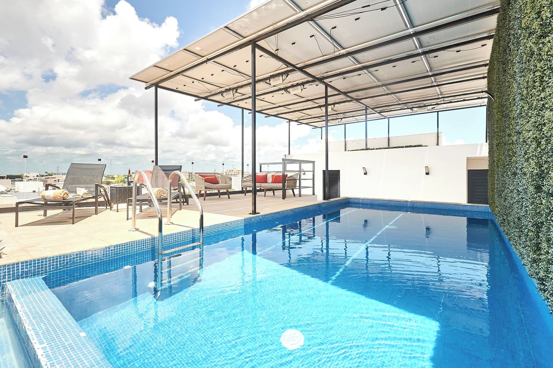 Une piscine sur le toit, dotée de chaises longues et d’un toit en verre.