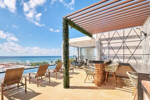 A rooftop terrace with a pool, outdoor seating, and a view of the ocean. - 2 Bdrm / ocean view / private pool / heart of town (Playa del Carmen)