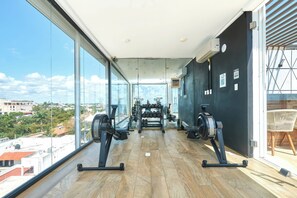 A gym with exercise equipment, large windows, and a view of the city. - 2 Bdrm / ocean view / private pool / heart of town (Playa del Carmen)