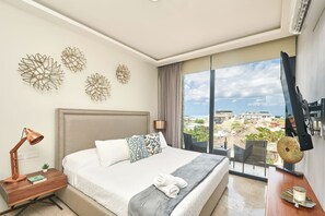 Une chambre d’hôtel moderne, dotée d’un grand lit, d’un bureau, d’une lampe et offrant une vue sur la ville.