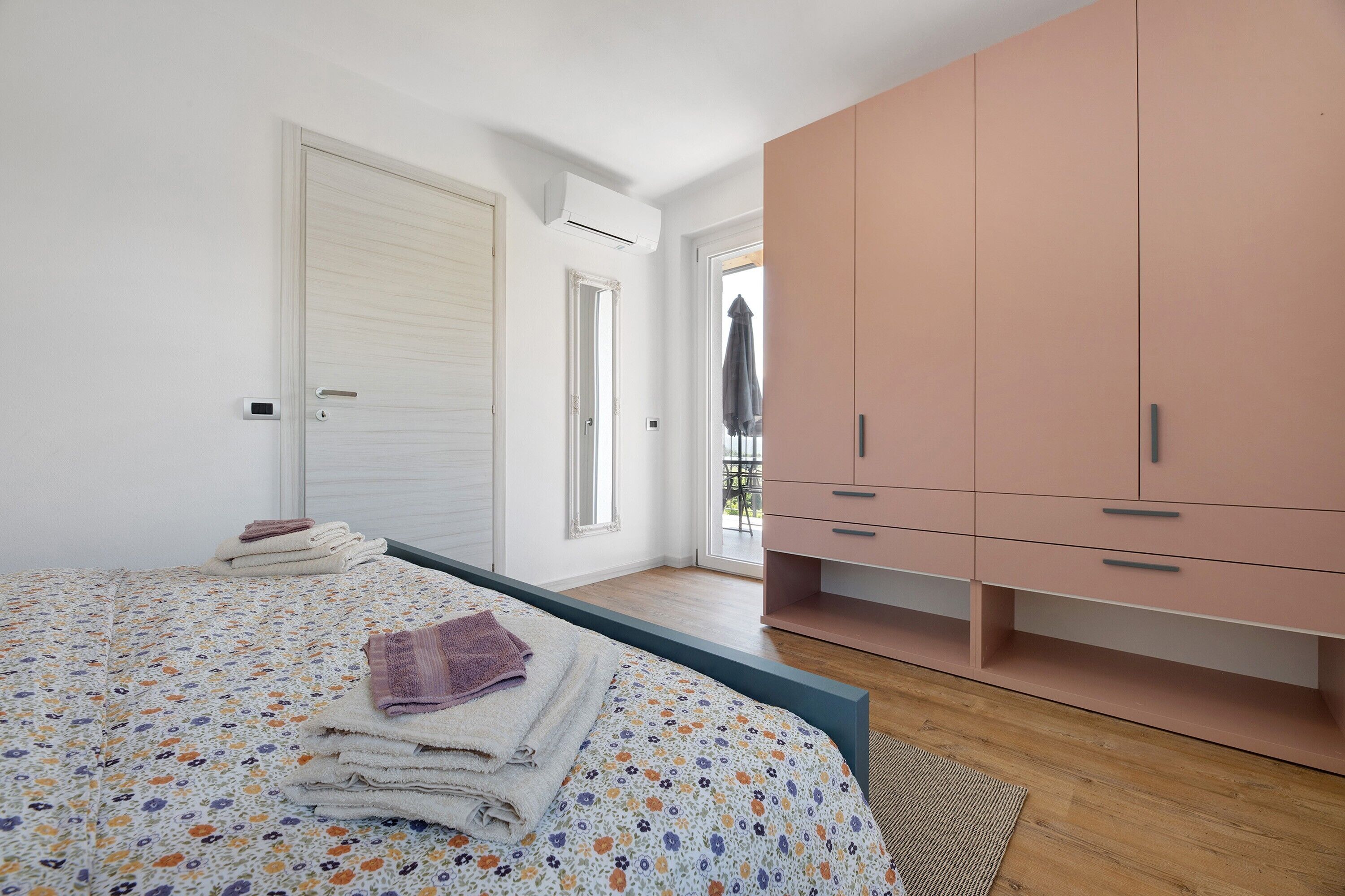 Una camera da letto con un letto, un armadio, una porta e vista sull'esterno.