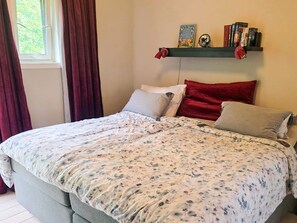A bedroom with a bed, a window with curtains, a bookshelf with books, and a wall-mounted shelf with decorative items. - 9 Person Holiday Home in Saeby (Sæby)