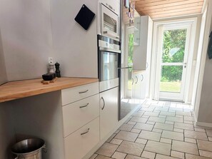 A kitchen with a wooden countertop, white cabinets, a stainless steel oven, and a view to the outdoors through a glass door. - 9 Person Holiday Home in Saeby (Sæby)