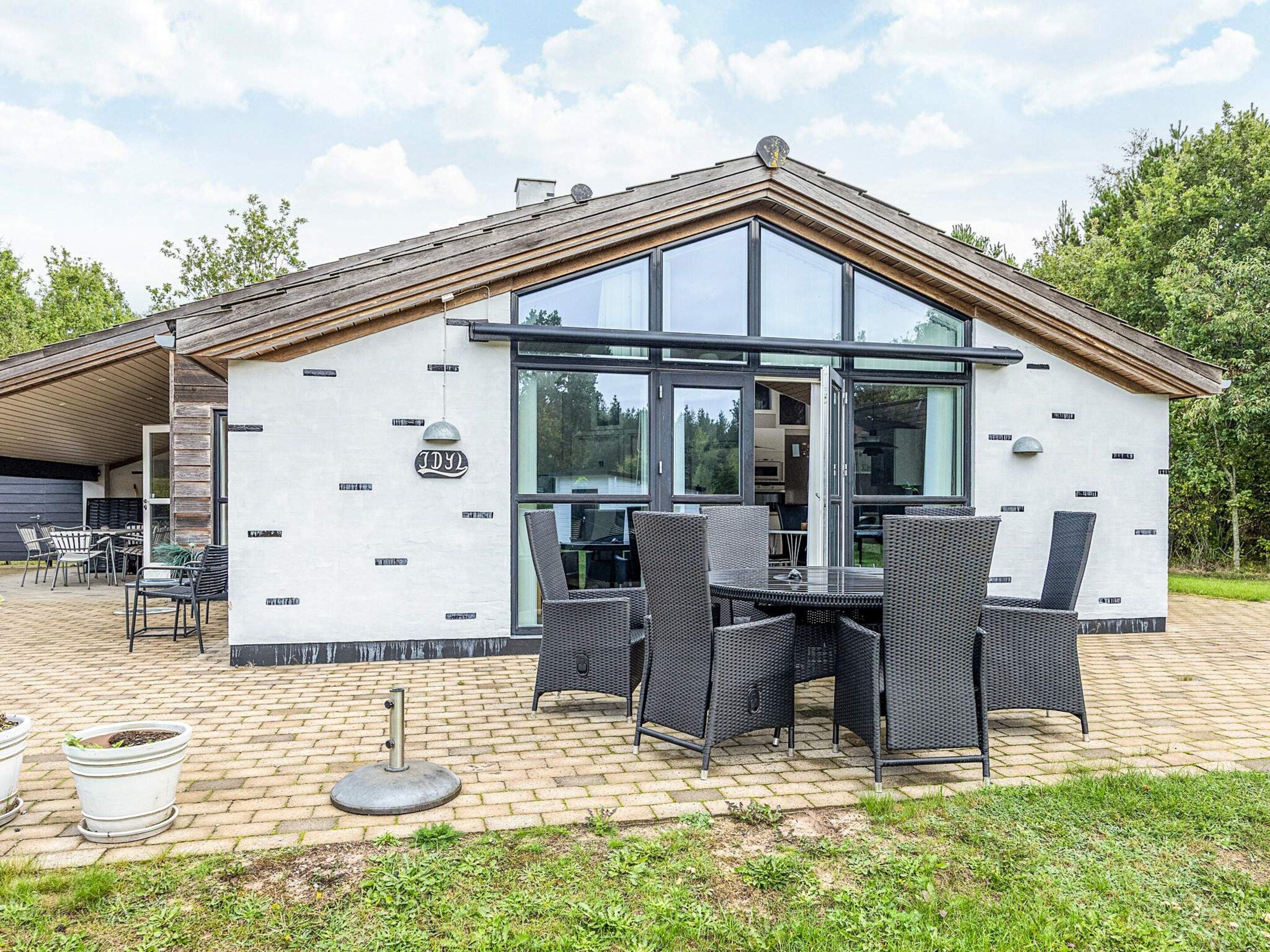 A modern building with a covered patio area featuring outdoor furniture and potted plants.