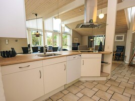 A modern kitchen with a wooden countertop, white cabinets, and a built-in dishwasher.