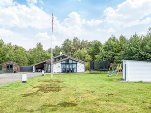 A residential area with a house, a flagpole, a trampoline, and a swing set. - 9 Person Holiday Home in Saeby (Sæby)