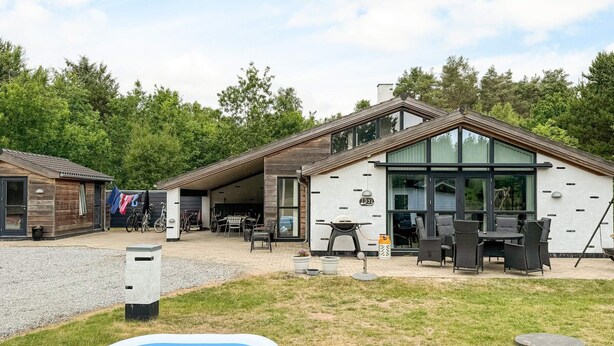 A modern house with a covered patio, outdoor seating, and a swimming pool. - 9 Person Holiday Home in Saeby (Sæby)