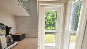 A kitchen with a coffee machine, a built-in oven, and a window with a view of greenery. - 9 Person Holiday Home in Saeby (Sæby)