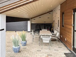 Un patio cubierto con mesa y sillas, plantas en macetas y una puerta de garaje.